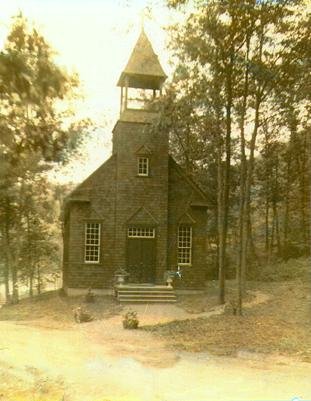 A small wooden church with a bell tower, nestled among trees at the Bischwind villa.