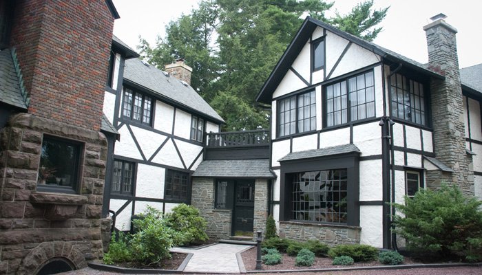 Tudor-style house with white stucco walls, dark timber framing, and a stone entryway.